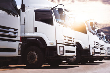 Semi Trucks on The Parking Lot at Sunset Sky. Big Rig. Tractor Truck. Shipping Cargo Container Trucks at The Port. Economy Business Transport on Road. Trucking. Freight Logistics Transport.	