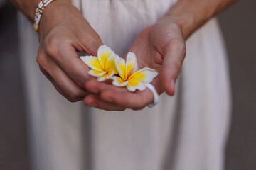young girl holds a white flower in her palm. A model poses with a flower in her clothes.