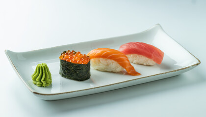 Minimalist sushi trio with salmon, tuna and salmon roe on white plate, elegant presentation