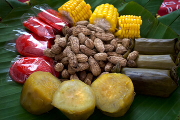 Boiled peanuts, sweet potatoes, sweet corns and traditional food from Indonesia, on green banana leaves