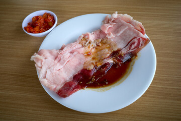 Fresh raw beef on a white plate ready to be grilled, on a wooden table
