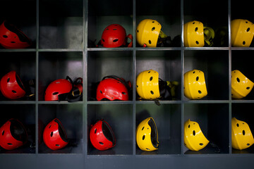 Red and yellow safety helmets lined up on a wooden shelf