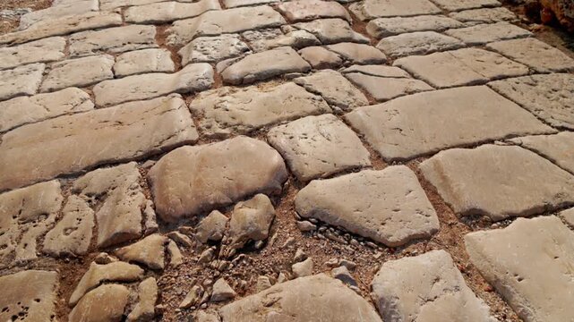 First person walk along an ancient stone road paved with large blocks in Zippori National Park, Galilee, Israel. Forward motion reveals weathered cobbles and historic texture underfoot
