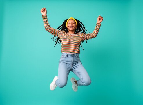 A joyful young woman jumping joyfully with her arms raised in celebration