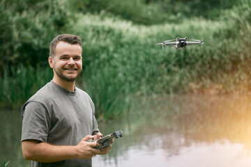 Man holding drone remote in green field.