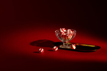 Glass Bowl of Peppermint Candies on Dark Red Background