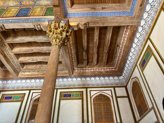 Ornate wooden mosque interior with carved pillars and painted ceiling