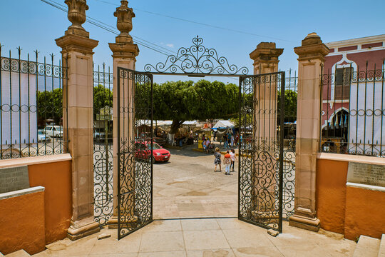 Decorative wrought-iron gate leading into a traditional Mexican plaza