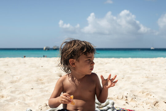 kid eating an orange on the beach on sunny day