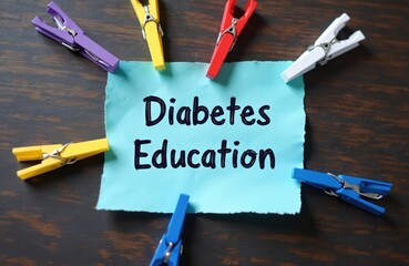 Turquoise paper note with text diabetes education held by colorful clothespins on dark wood table. Medical awareness learning concept. Teaching disease management.