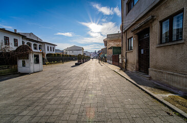 Targoviste, Romania Dec 26, 2025 - Sunny street scene featuring the School of Arts building, with the sun visible in the frame, starburst effect from aperture, and a clear blue sky with few clouds