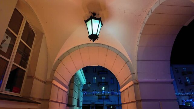Historic arcades at night with hanging lantern, vaulted passageway, urban architecture, warm ambient lighting