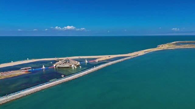 Qinghai Lake, Qinghai Province, China - Turquoise Water is Divided by a Long Causeway, with a Circular Lakeside Structure Set Against a Vast Open Horizon - Aerial Drone Shot