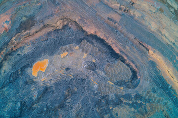 Industrial open pit mine with toxic waste and curved terraces, polluted soil texture and orange sludge, aerial top view drone shot