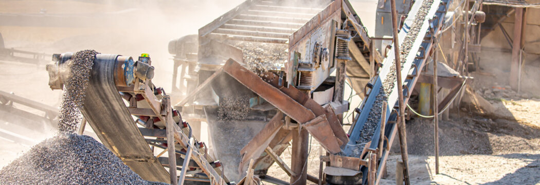 Vibrating screen stone crusher in operation. Crushing stones in a quarry for processing minerals, cement, limestone. Heavy and mobile equipment in a quarry for processing stone into building material.