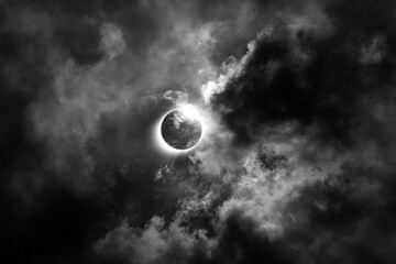 A solar eclipse occurs as the moon partially covers the sun, with dark clouds creating a dramatic backdrop in the sky