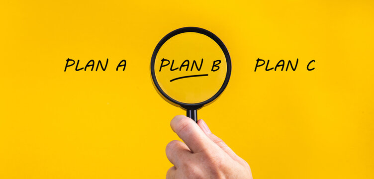 Hand holding magnifying glass focusing on plan b