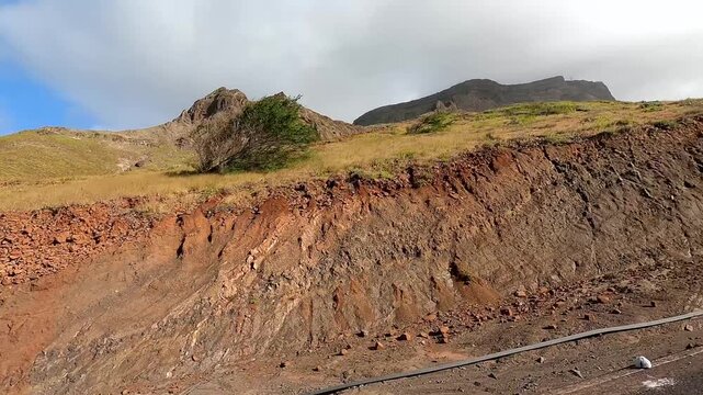 Ascending around bend on Monte Verde on S&atilde;o Vicente Island, Cape Verde on road with white stone wall with mountain in distance