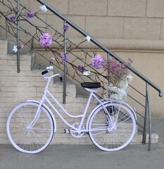 White bicycle near stone wall and staircase decorated with flowers.