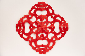 A symmetrical red paper cutting on a white background.