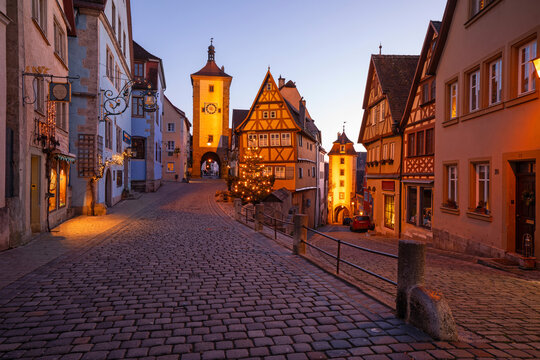 Dezember 2025 Weihnachtszeit am Pl&ouml;nlein &ndash; Rothenburg ob der Tauber, Bayern, Deutschland. Festlicher Christbaum und Stadtlichter zur blauen Stunde.