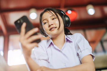 asian girl teen looking at smart phone listening music, online education, watch live teaching