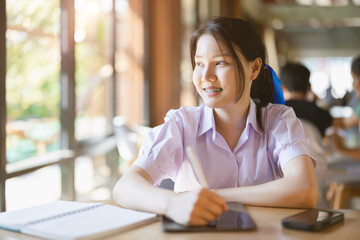 Asian teen girl , high school student female Thai uniform at school campus library happy smiling