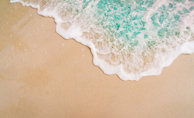 A close-up, high-angle of a gentle white-foamed ocean wave washing onto a smooth sandy beach © avtk