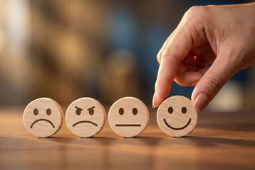 Choosing positive emotions hand selecting a happy face from wooden expression blocks