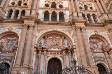 Obraz premium Detailed facade of the Renaissance Cathedral of Malaga showcasing intricate stone carvings, massive columns, and arched portals, highlighting the architectural heritage of religion in Spain.