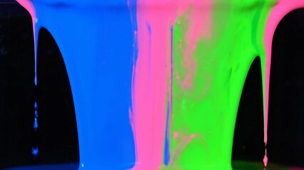 Colorful paint dripping against a black backdrop