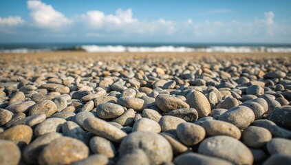Obraz premium Tranquil Beach Scene with Pebbles and Waves Under a Blue Sky