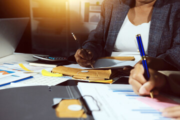 business documents on office table with tablet, smart phone and laptop and two colleagues discussing data
