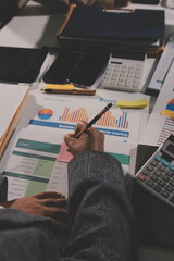 business documents on office table with tablet, smart phone and laptop and two colleagues discussing data
