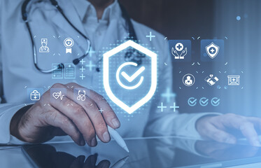 Doctor interacting with digital hologram interface showing health insurance and medical icons on futuristic screen in healthcare concept setting.