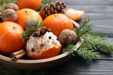 Ripe tangerines, spices, walnuts, fir tree branches and cone on wooden table, closeup