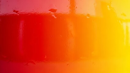 Vibrant abstract glossy glass texture background featuring a shiny glass surface with a red to yellow gradient. Modern and energetic backdrop 