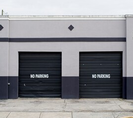 Two Black Roll Up Garage Doors with No Parking Text