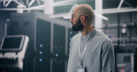 IT Professional Inspecting Rows of Active Server Racks. Male Engineer Walks Large Data Center, Conducting Physical Inspection of Glowing Server Racks. Security Protocol, Infrastructure Surveillance.