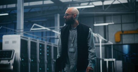 Professional Engineer Walking Through High Tech Facility. IT Supervisor in Dark Vest and Shirt Walks Purposefully Through Large Server Facility. Concept Professional Oversight, Monitoring and Control.