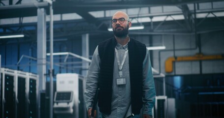 Professional Engineer Walking Through High Tech Facility. IT Supervisor in Dark Vest and Shirt Walks Purposefully Through Large Server Facility. Concept Professional Oversight, Monitoring and Control.