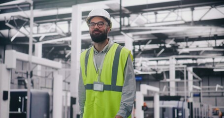 Engineer Communicating Via Walkie Talkie in Factory. Bearded Engineer in Hard Hat and Safety Vest Uses Walkie Talkie Coordinate Teams on Large Industrial Site. Operational Report, Project Management.