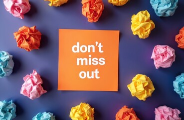 Orange paper with do not miss out text is surrounded by colorful crumpled paper balls on a purple background. It represents ideas, planning, and missed opportunities in work.