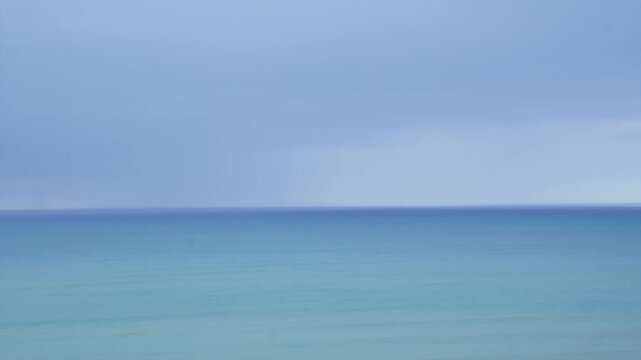 Calm ocean and soft overcast sky with a clear horizon. Minimalist seascape with subtle movement, peaceful and atmospheric background. Relaxation, mindfulness, wellness concepts, and copy space.