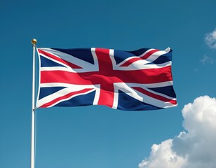 United Kingdom flag, Union Jack, waves against blue sky with clouds. Fabric flutters on flagpole in bright daylight. National symbol of Britain blows in fresh breezy wind.