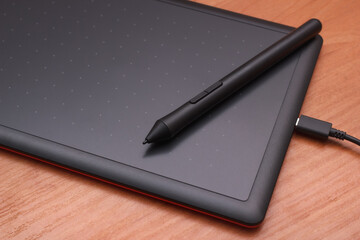 Digital drawing tablet with a pen on the desk. Electronic device for creative painting, graphic design and photo retouching. Closeup view.