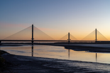 Obraz premium Mersey Gateway Bridge spanning the River Mersey at sunrise with exposed mudflats at low tide