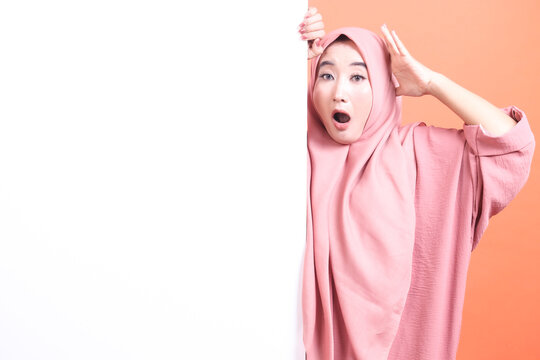 Startled muslim lady with wide eyes holding a blank banner exhib