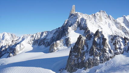 Panoramic winter landscape of snow-covered alpine mountains near Mont Blanc in the Italian Alps. Pristine glacier scenery, dramatic peaks and untouched nature under clear sky.