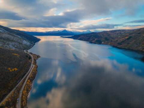 Aerial View of a Calm Fjord With Reflections and a Winding Coastal Road in Northern Norway